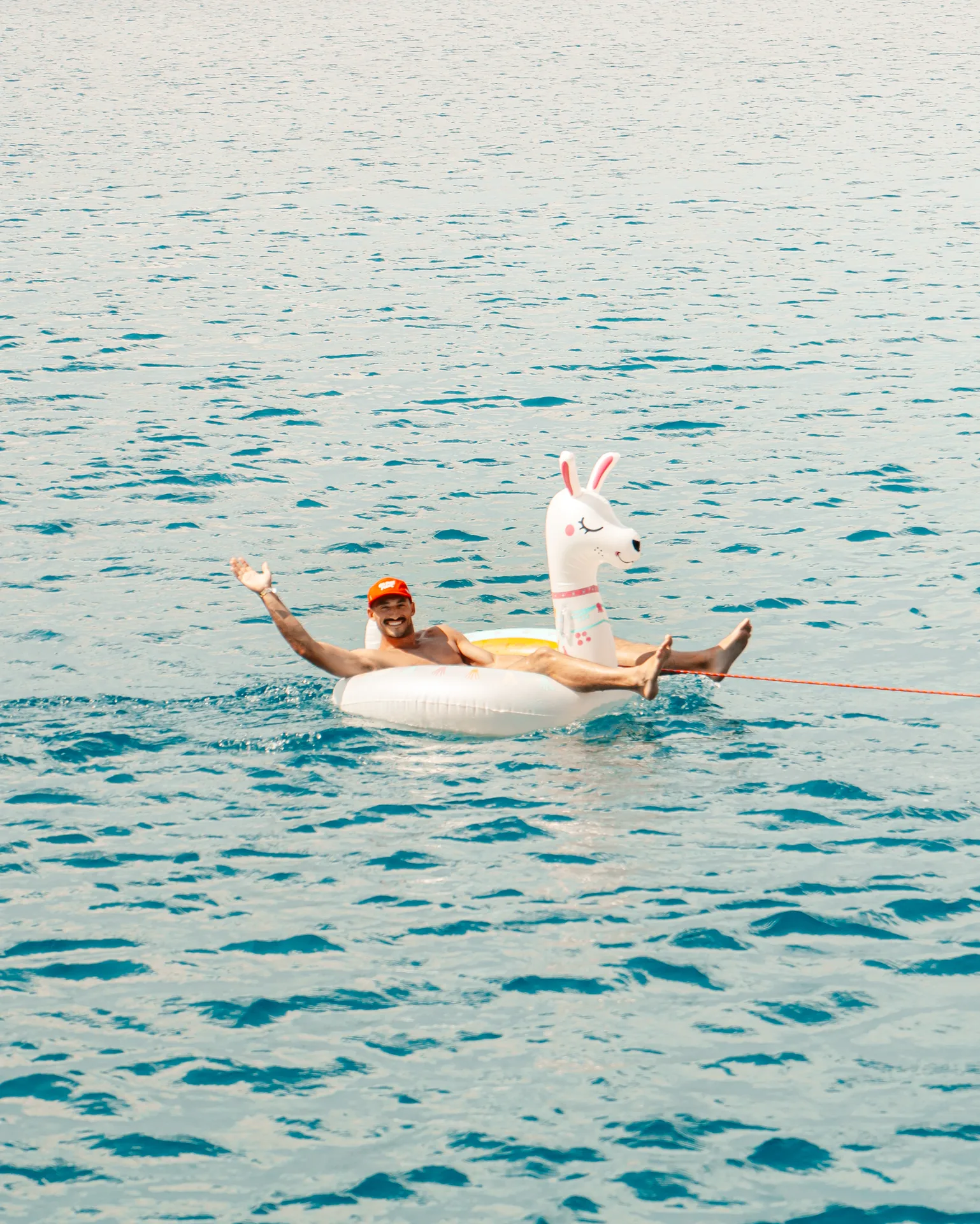 A solo traveller floating in the sea on an inflatable llama